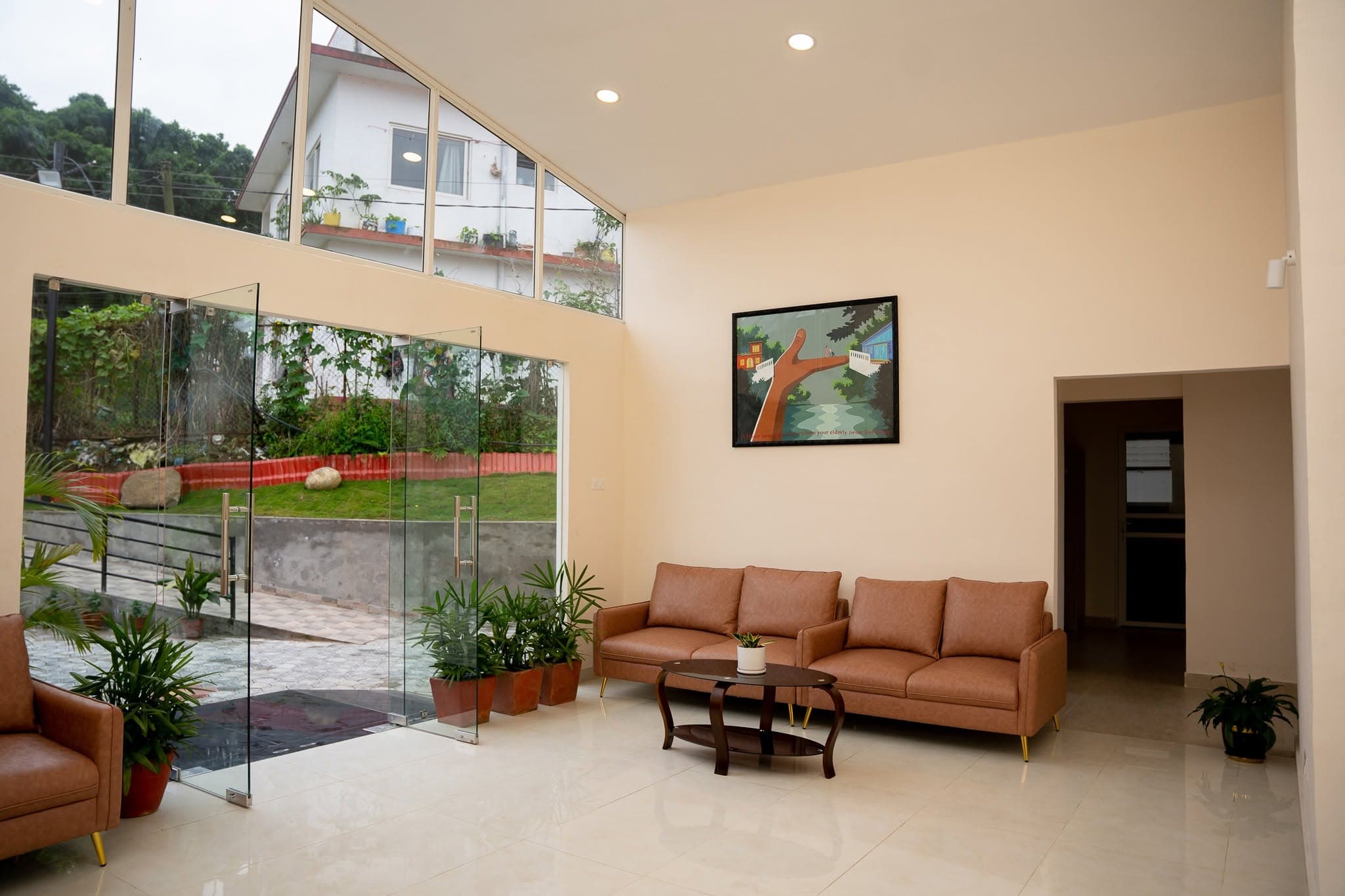 The bright double-height lobby at Naman Bansbari with the garden through glass doors — a place to spend the day