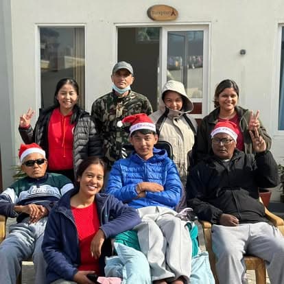 Naman residents and staff in Santa hats, throwing peace signs together at Christmas