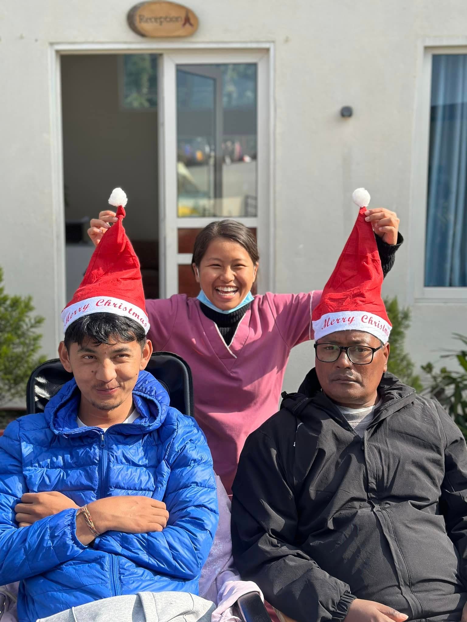 A Naman nurse and two residents in Santa hats, laughing together at Christmas