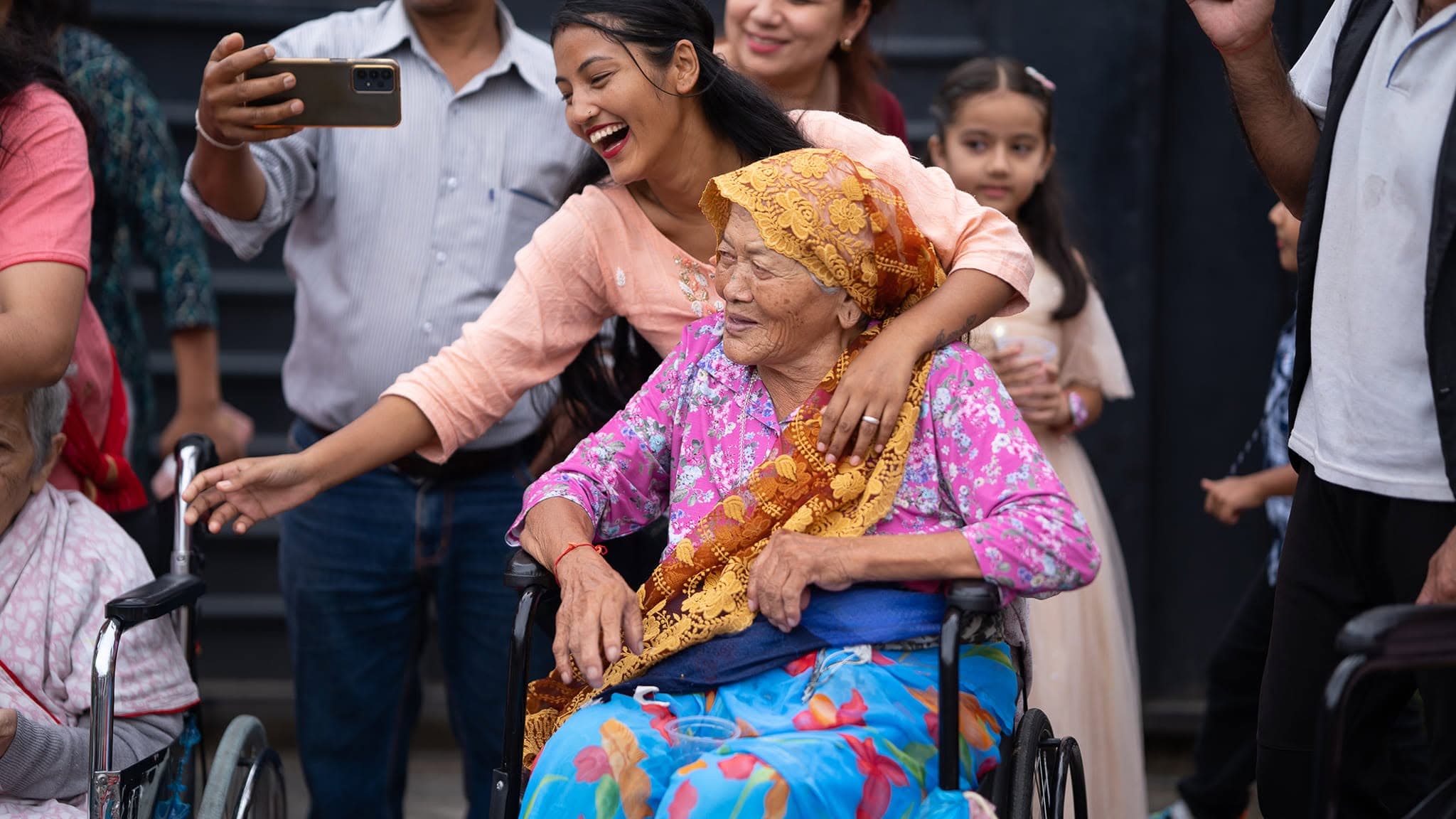 A visiting family taking a joyful selfie with an elderly resident at Naman — everyday elderly care