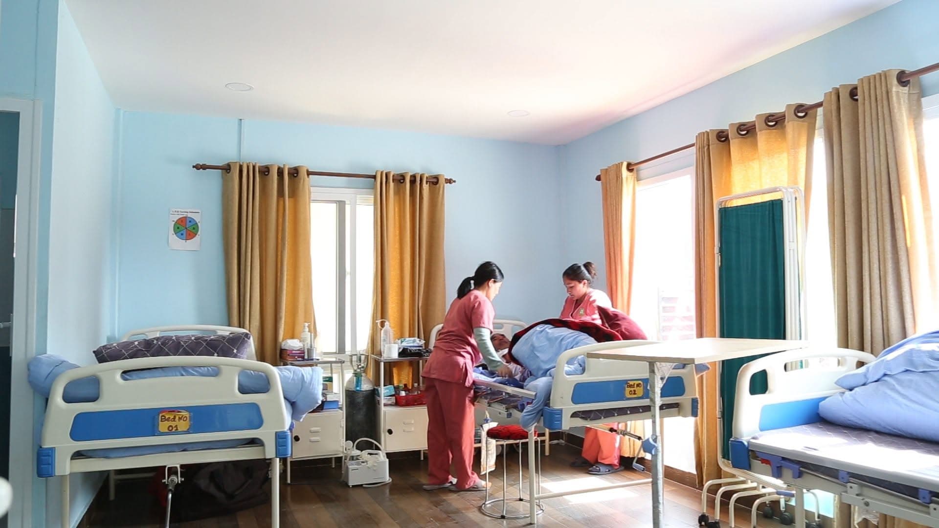 Two Naman nurses turning a resident during the morning round — the close attention of post-hospital care