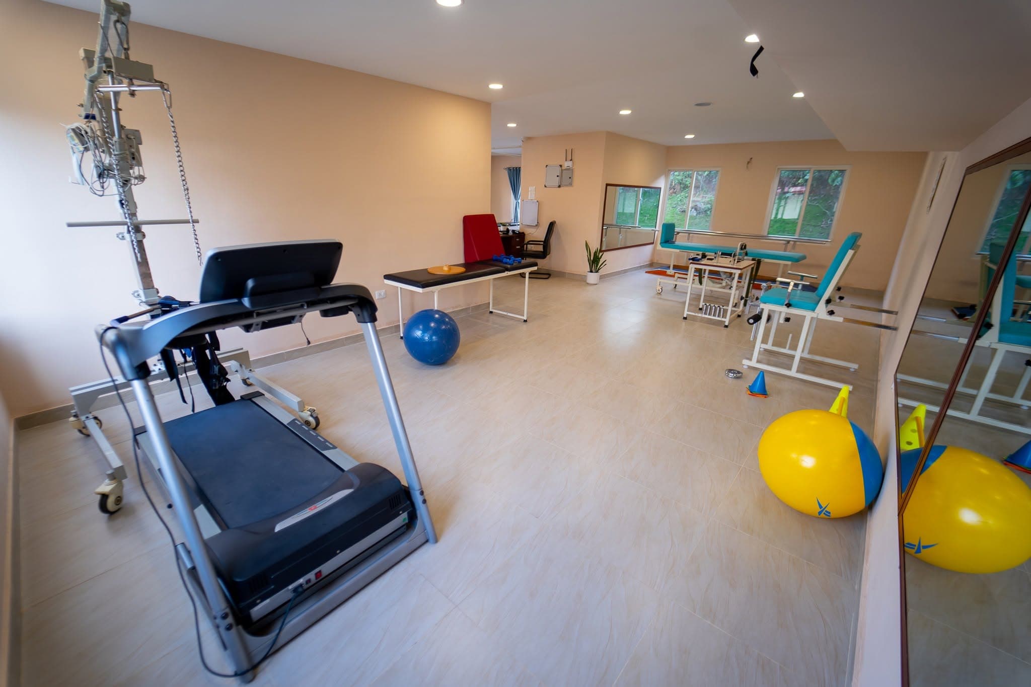 The Naman Bansbari physiotherapy room — standing frame, treadmill, and exercise balls set up for a full rehabilitation session
