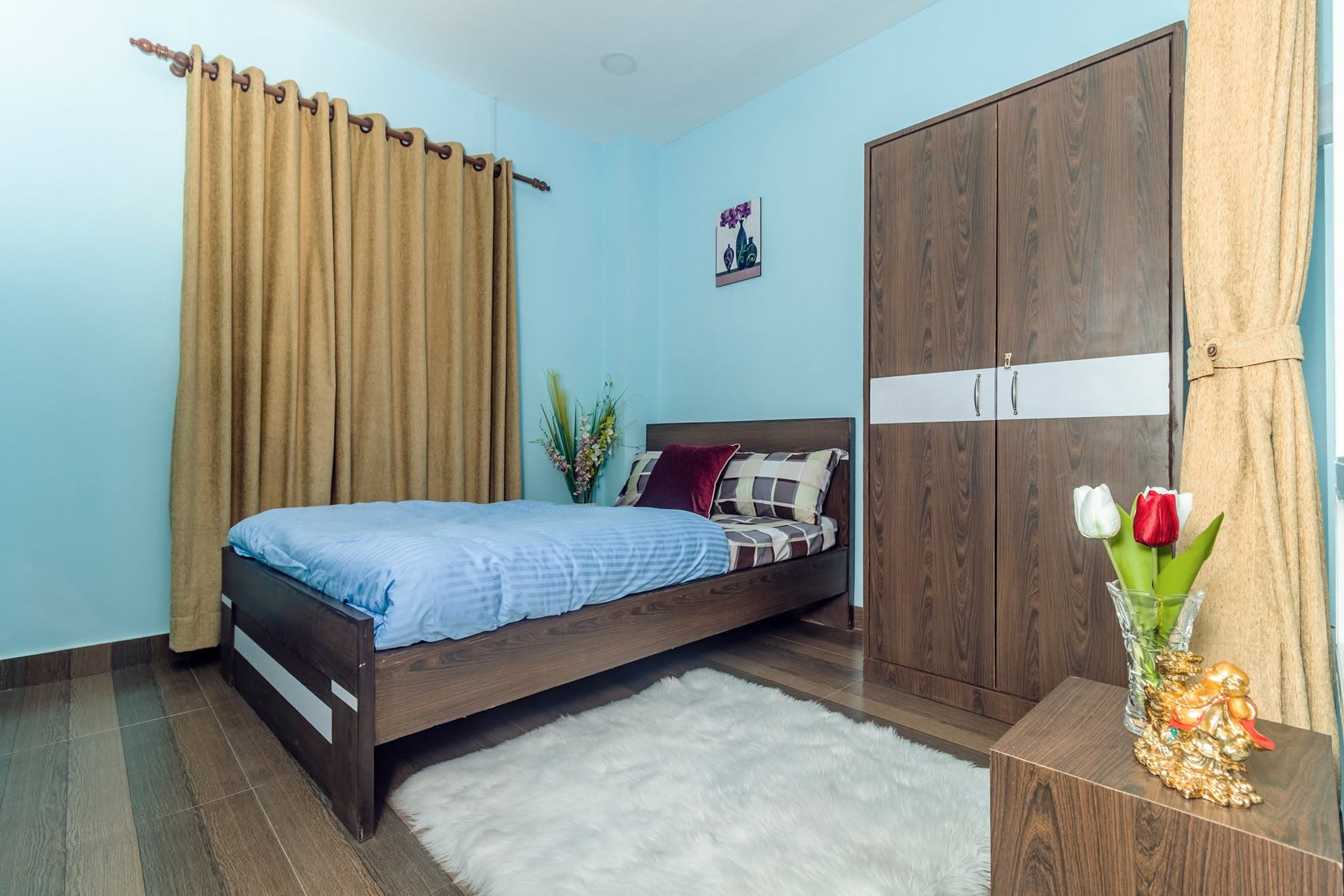 A private cabin at Naman Pipalbot — a single bed with wardrobe, wooden floor and warm curtains