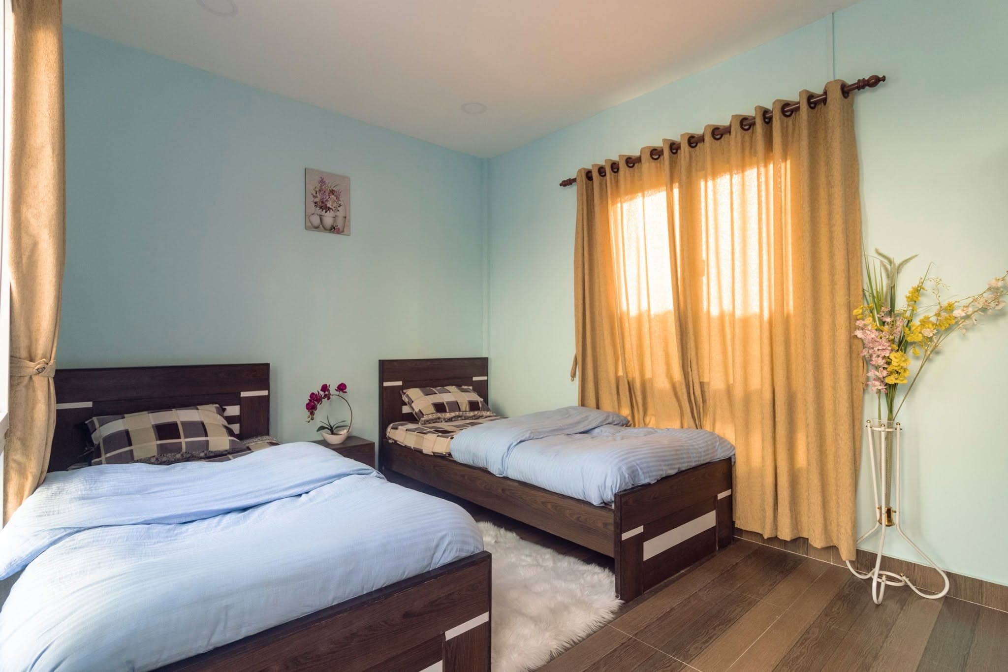 A smaller shared room at Naman Pipalbot — two wooden beds with blue linens and warm afternoon light