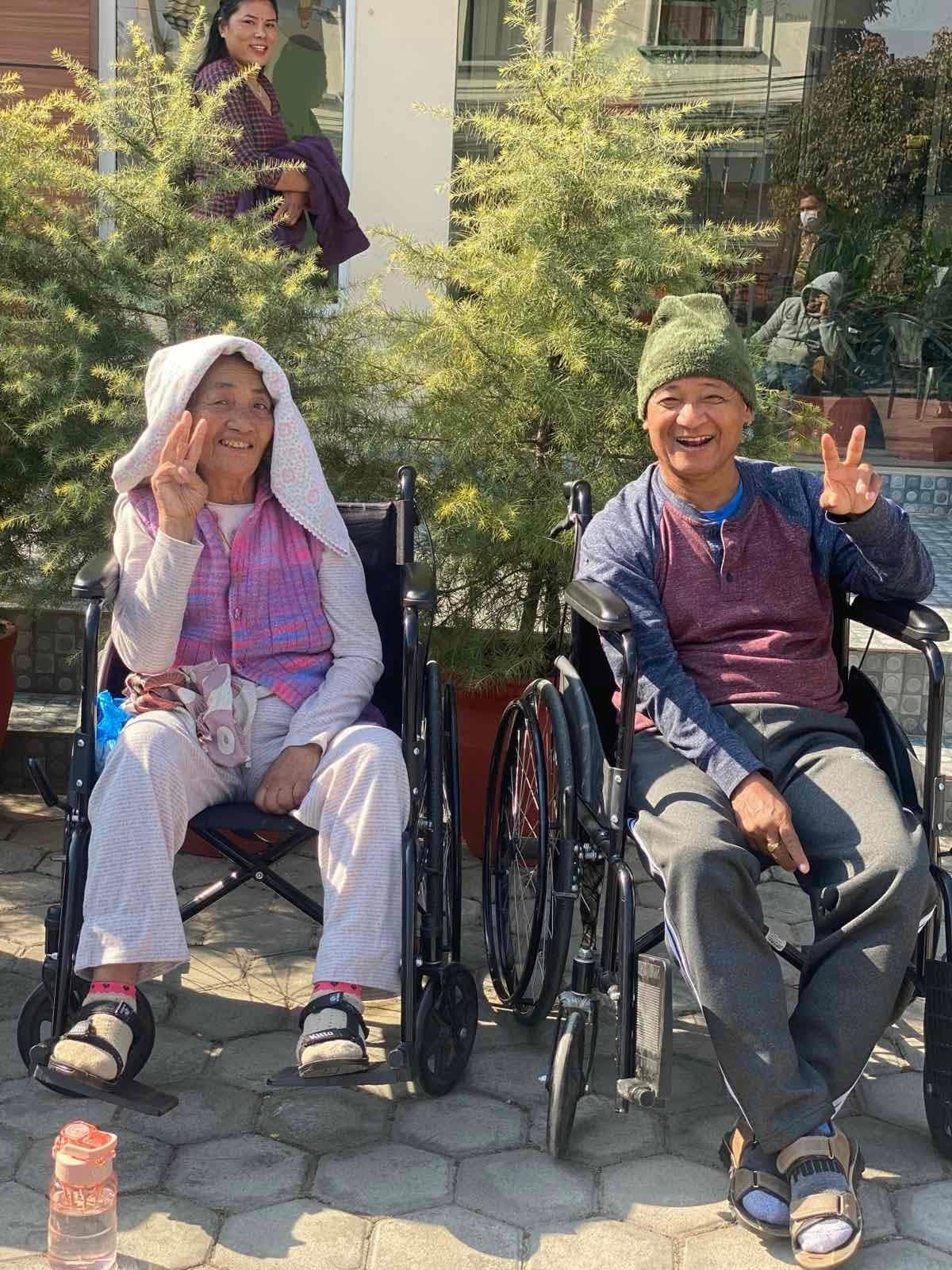 Two Naman residents smiling and giving a peace sign together