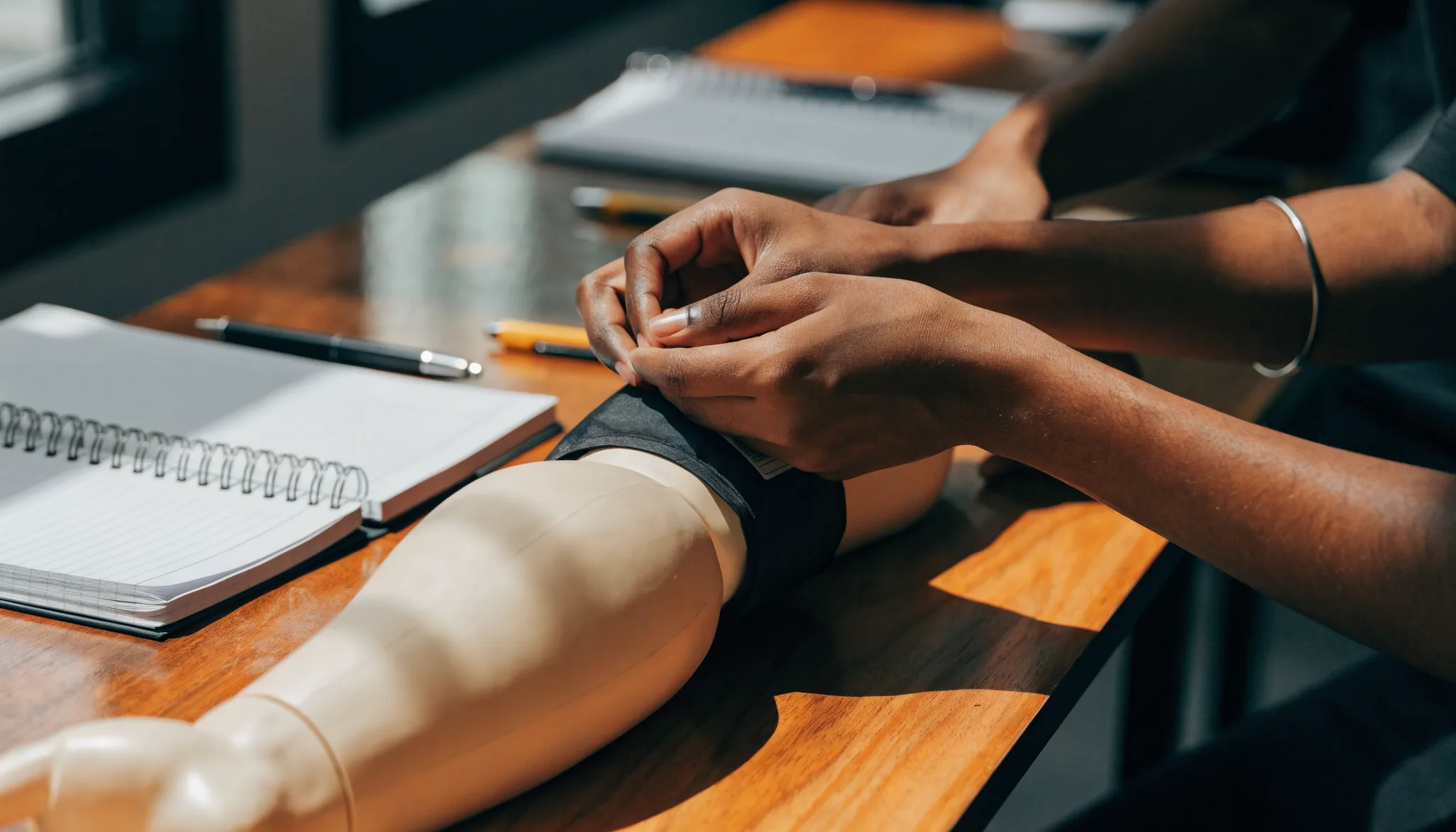 Close-up of hands practising a blood-pressure cuff on a training mannequin arm